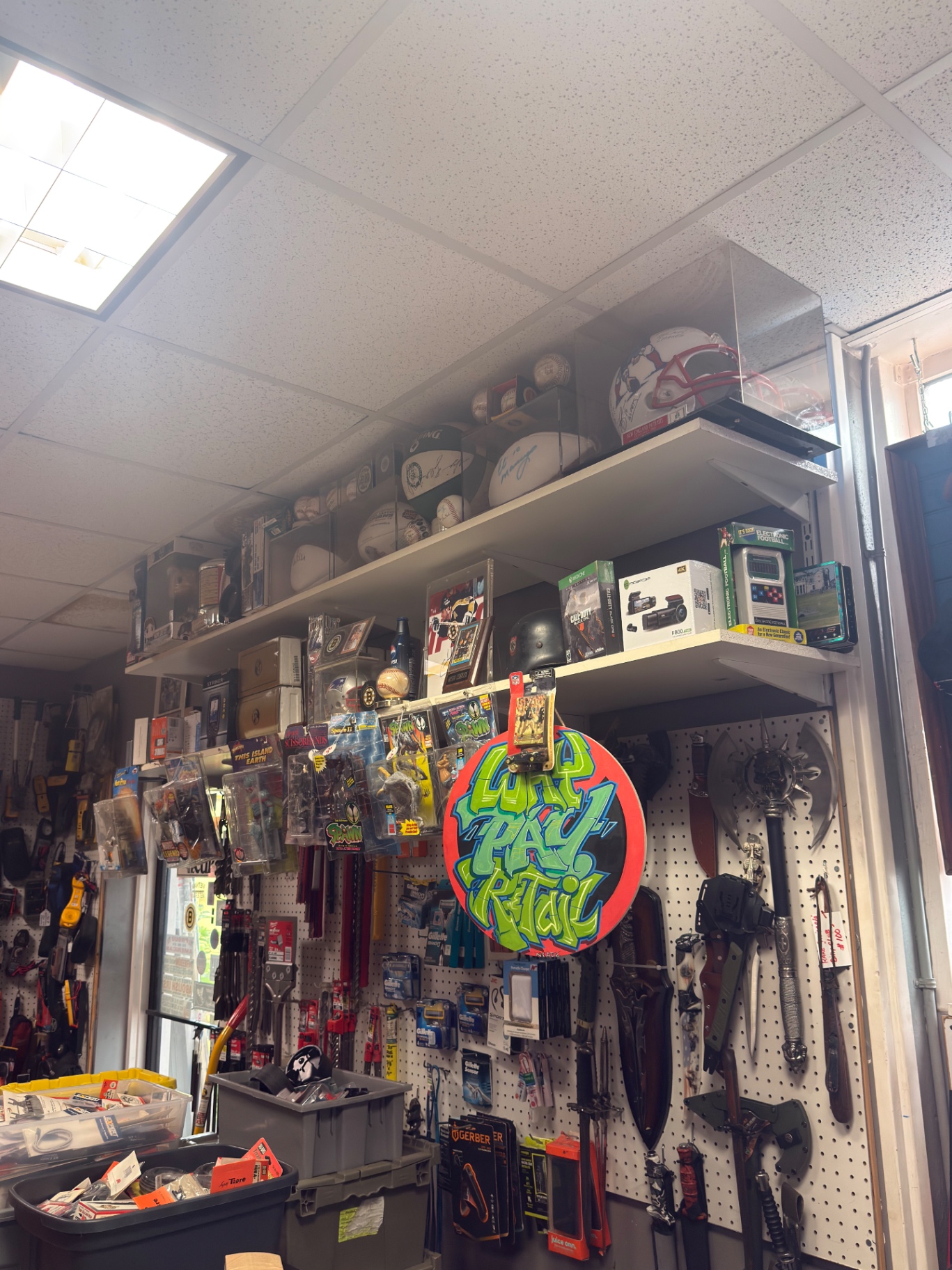 Signed footballs, helmets, and Spawn figures above pegboard of knives